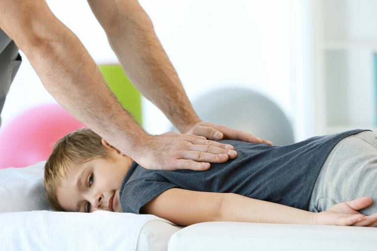 A chiropractor performing a gentle spinal adjustment on a patient lying on an exam table.