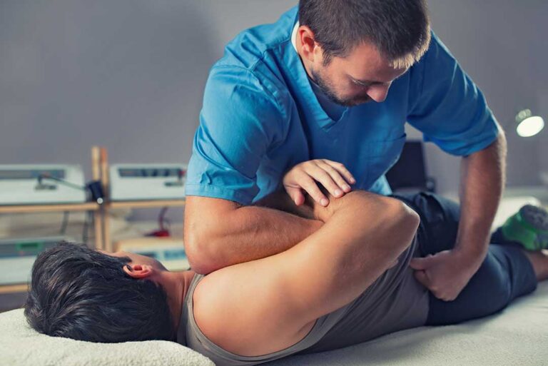 Patient discusses back pain with a chiropractor during a first visit in a bright examination room.